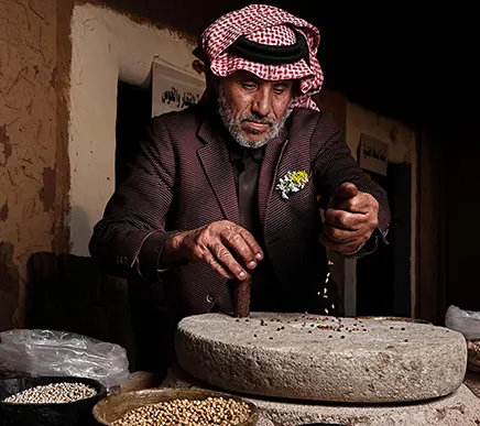Middle Eastern man using traditional methods to grind spices